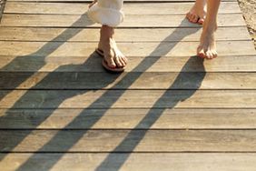 2 pairs of feet walking on a beach boardwalk