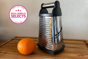 A cheese grater we recommend displayed on a wooden cutting board with an orange