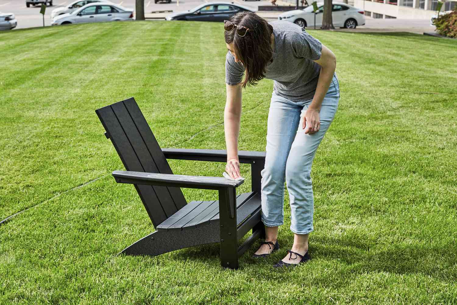 Person wiping the arm of the Polywood Modern Adirondack Chair outside 