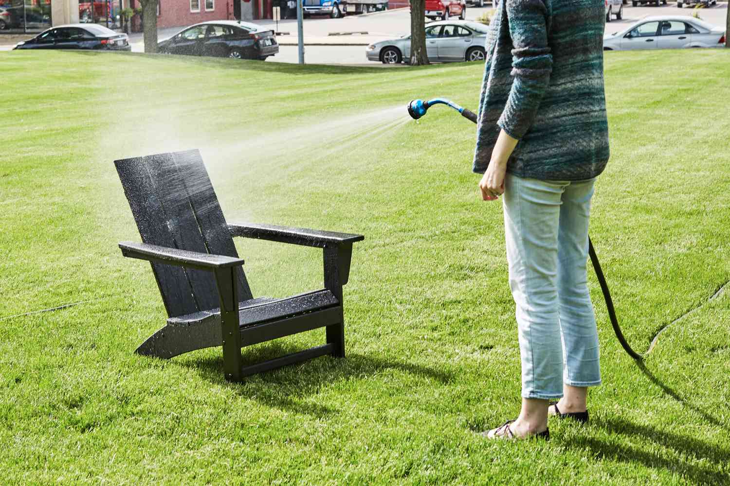 Person spraying the Polywood Modern Adirondack Chair with a hose