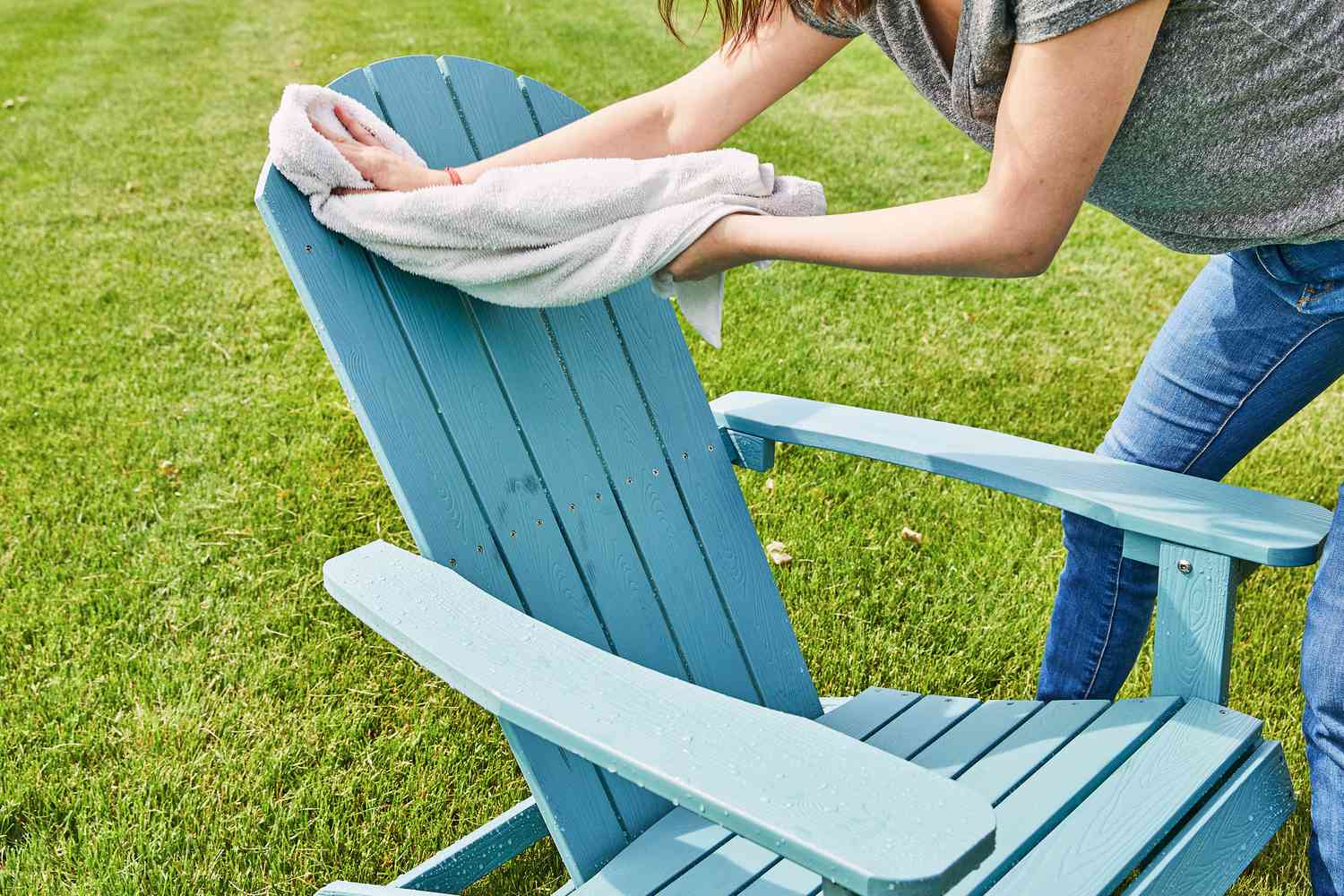 Person using a white towel to wipe the Yefu Plastic Adirondack Chair outside 