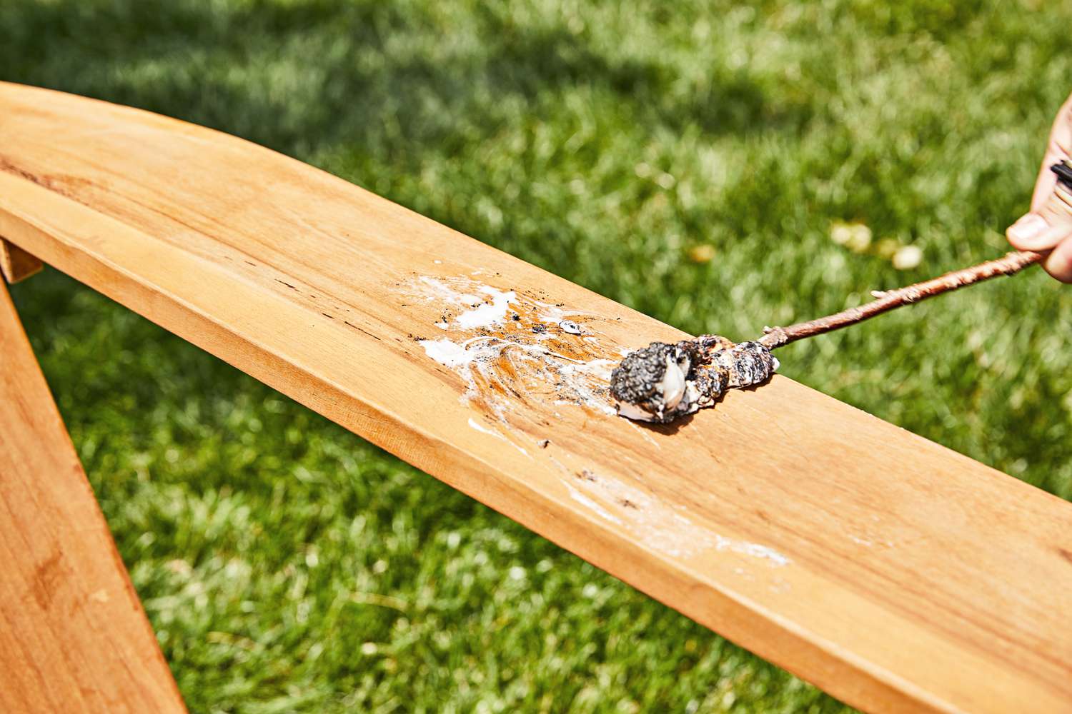 Hand smearing marshmallow on the armrest of the Grandin Road All-Natural Teak Adirondack Chair outside 