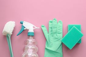 Teal bathroom cleaning brush, spray bottle, rubber gloves, and sponges