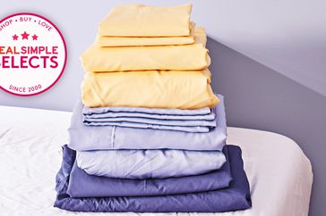 Folded yellow and blue cooling bed sheets in a stack on a bed