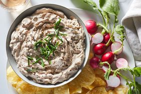 overhead view of bowl of Deeply Caramelized Onion Dip surrounded by chips and radishes