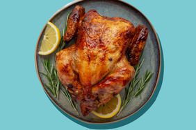 rotisserie-chicken- on plate with lemons and rosemary