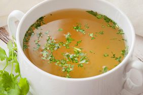 Bone Broth Benefits: Cooked hot bone broth with spices and fresh herbs.