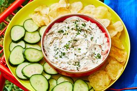 Caramelized shallot dip is served with potato chips and sliced cucumber.