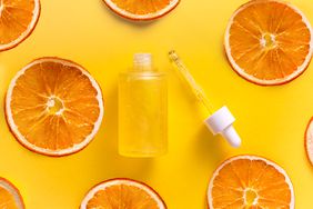 serum surrounded by orange slices on a yellow background