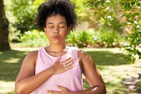 Woman in athletic clothing doing breathing exercises mindful meditation outside in a park