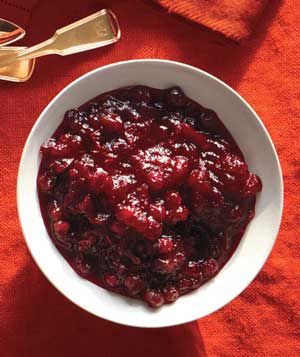 Bourbon-Cranberry Compote Served in a White Bowl Against an Orange Background