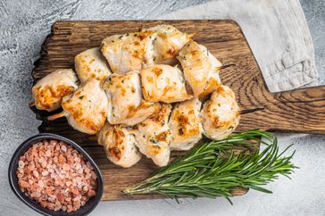 Chicken kebab skewers with onion and spices on wooden board. White background. Top view.