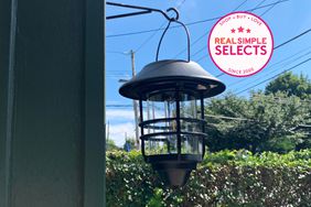 Derynome Solar Lantern Outdoor Lights with Wall Mount Kit hanging on a hook outside