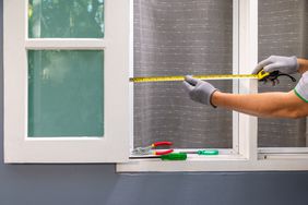 Man measuring wooden window frame for installation net screen insect.