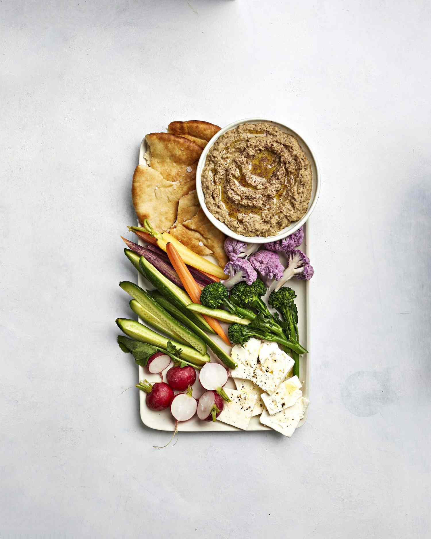 Eggplant Dip in a Small Bowl Served With Feta and Crudités on a White Serving Platter