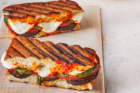 Two eggplant parmesan paninis are placed on a cutting board.