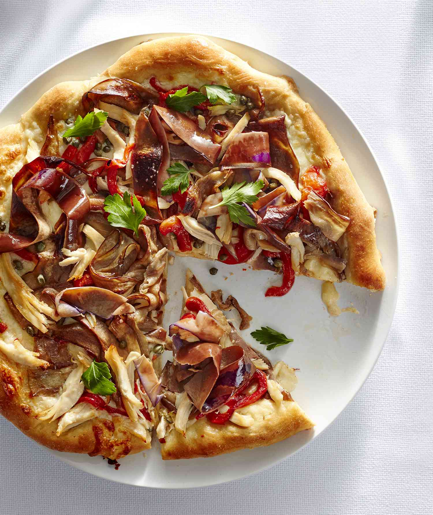 Eggplant and Chicken Caponata Pizza With One Slice Cut Out, Served on a Circular White Plate