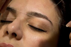 Professional eyebrow hair removal service on a woman in a hair salon.