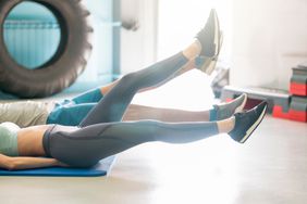 Woman and man doing flutter kick ab exercise at home 