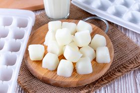 Milk ice cubes on a cutting board a white wooden table