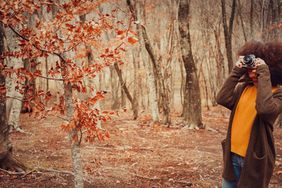 fun-things-to-do-november: woman taking pictures of fall foliage