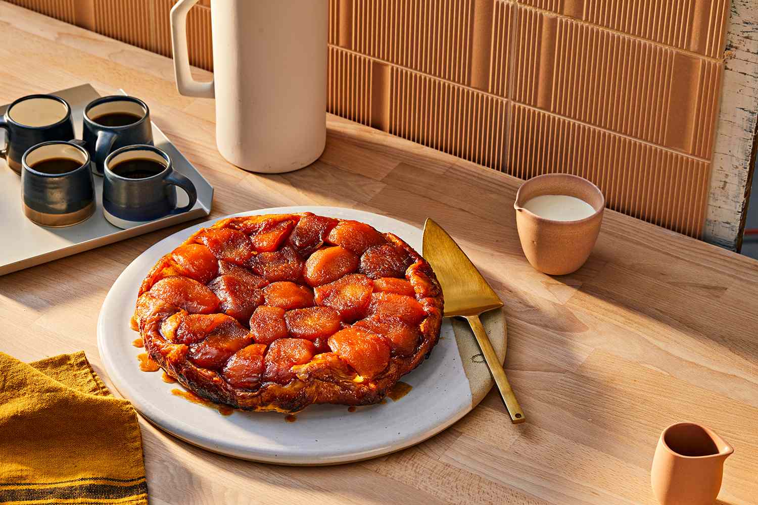 Ginger Apple Tarte Tatin Served on a Large Tray With a Serving Knife, Surrounded by a Tray of Coffee Mugs