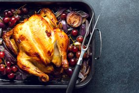 Whole Roasted Turkey in a Roasting Pan With Grapes and Onions and a Carving Fork