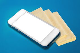 White Cell Phone With a Blank Screen on Top of Three Tan Cleaning Cloths, All Against a Blue Background