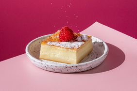 square piece of cake on a plate with a pink background