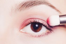 Eye makeup. Woman applying pink eyeshadow powder. Close up shot