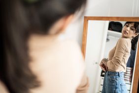 A woman trying on jeans in a mirror