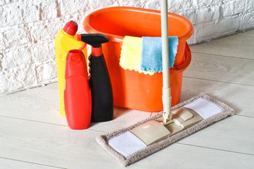 Various cleaning items and supplies, mop with orange bucket on the floor. House cleaning service concept