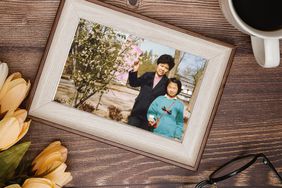 framed photo of mother and child displayed on a wooden table next to a coffee cup and flowers