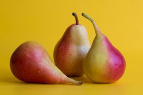 Three red yellow fresh pears isolated on yellow background.