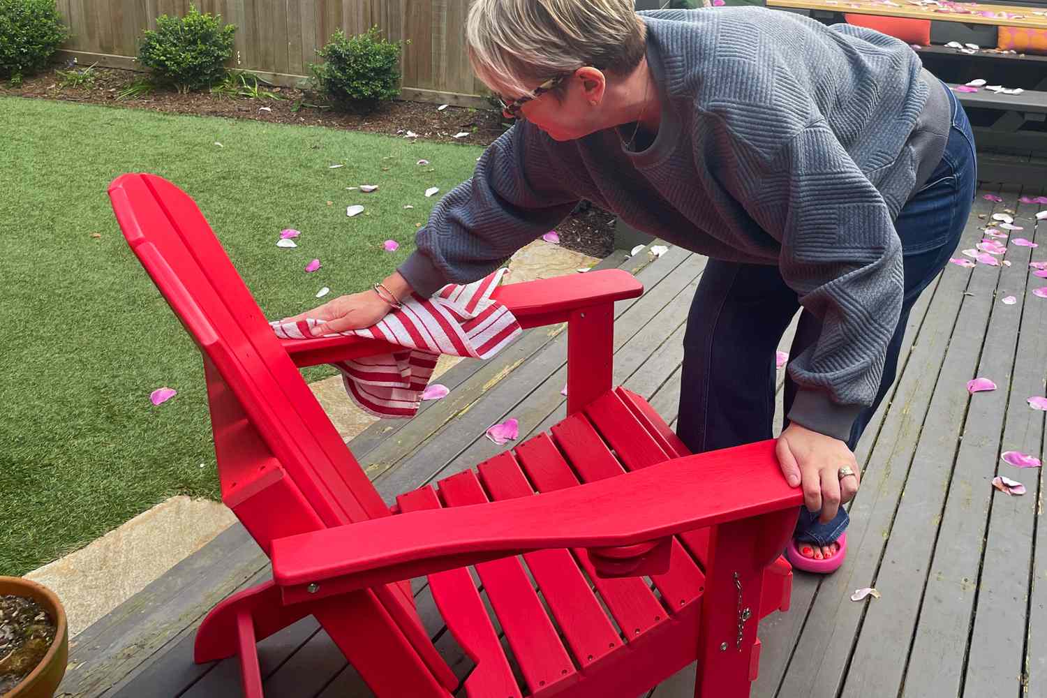 A person rubbing the Ciokea Folding Adirondack Chair with a towel