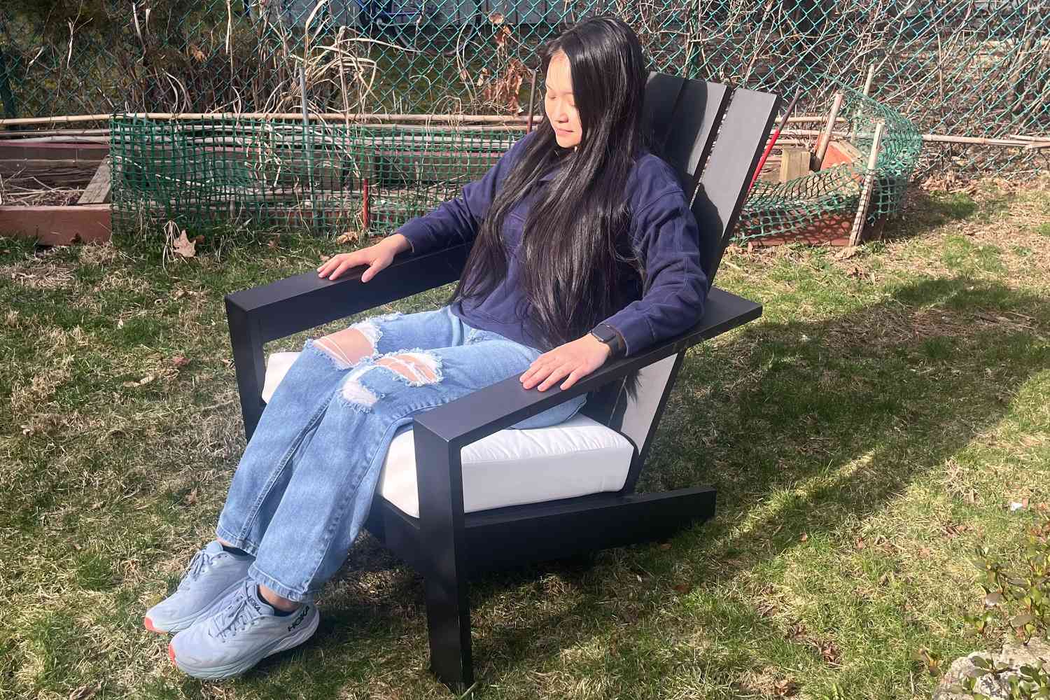 A person sitting on the Pottery Barn Malibu Metal Adirondack Outdoor Lounge Chair