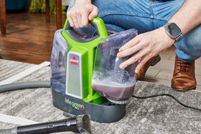 A person removing the dirty water tank from the BISSELL Little Green ProHeat Portable Carpet Cleaner