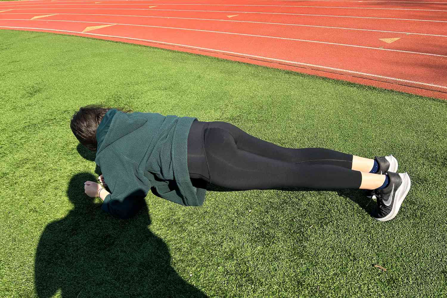 A person does a plant on grass while wearing the Spanx Booty Boost Active 7/8 Leggings