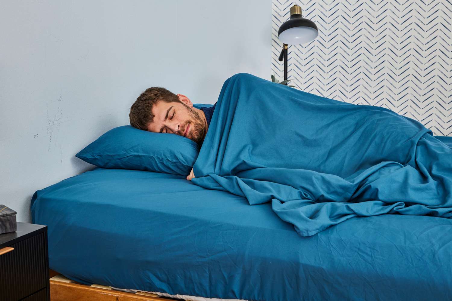 A person laying on a bed made with the Comfort Spaces Coolmax Moisture Wicking Sheet Set