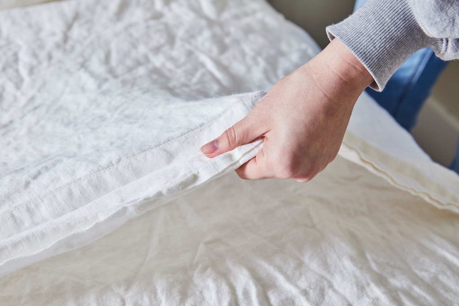 Hand feeling the surface of the Saatva Linen Sheet Set