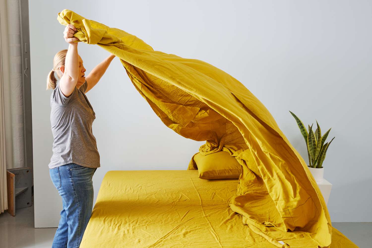 person makes bed with ettitude Linen+ Sheet Set