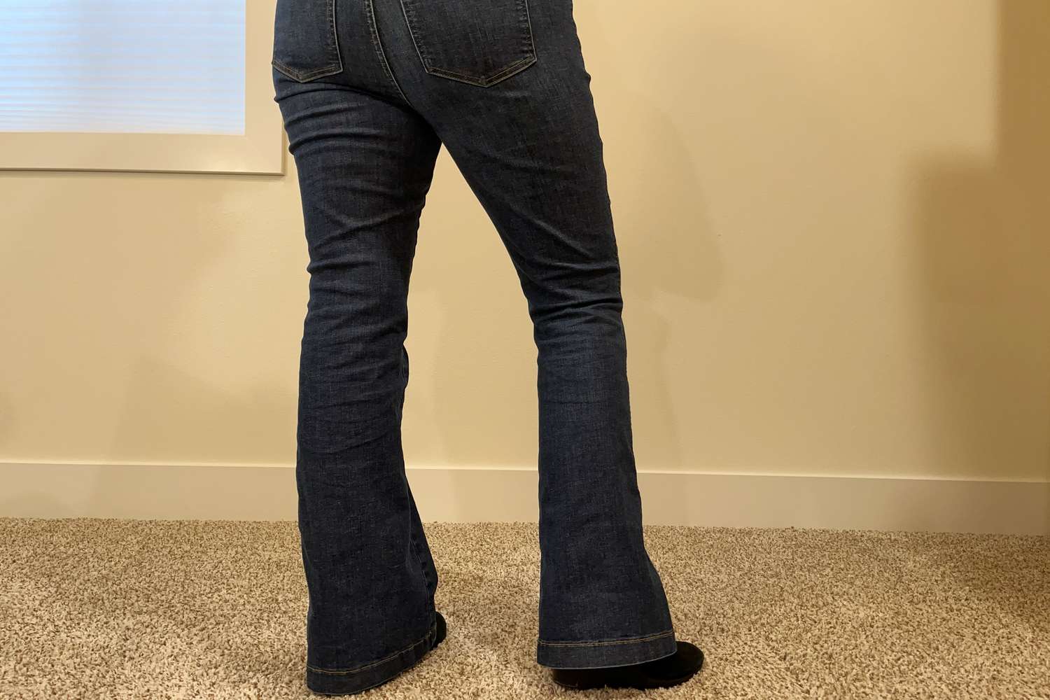 Backside of a person wearing Spanx Flare Jeans while standing on carpet