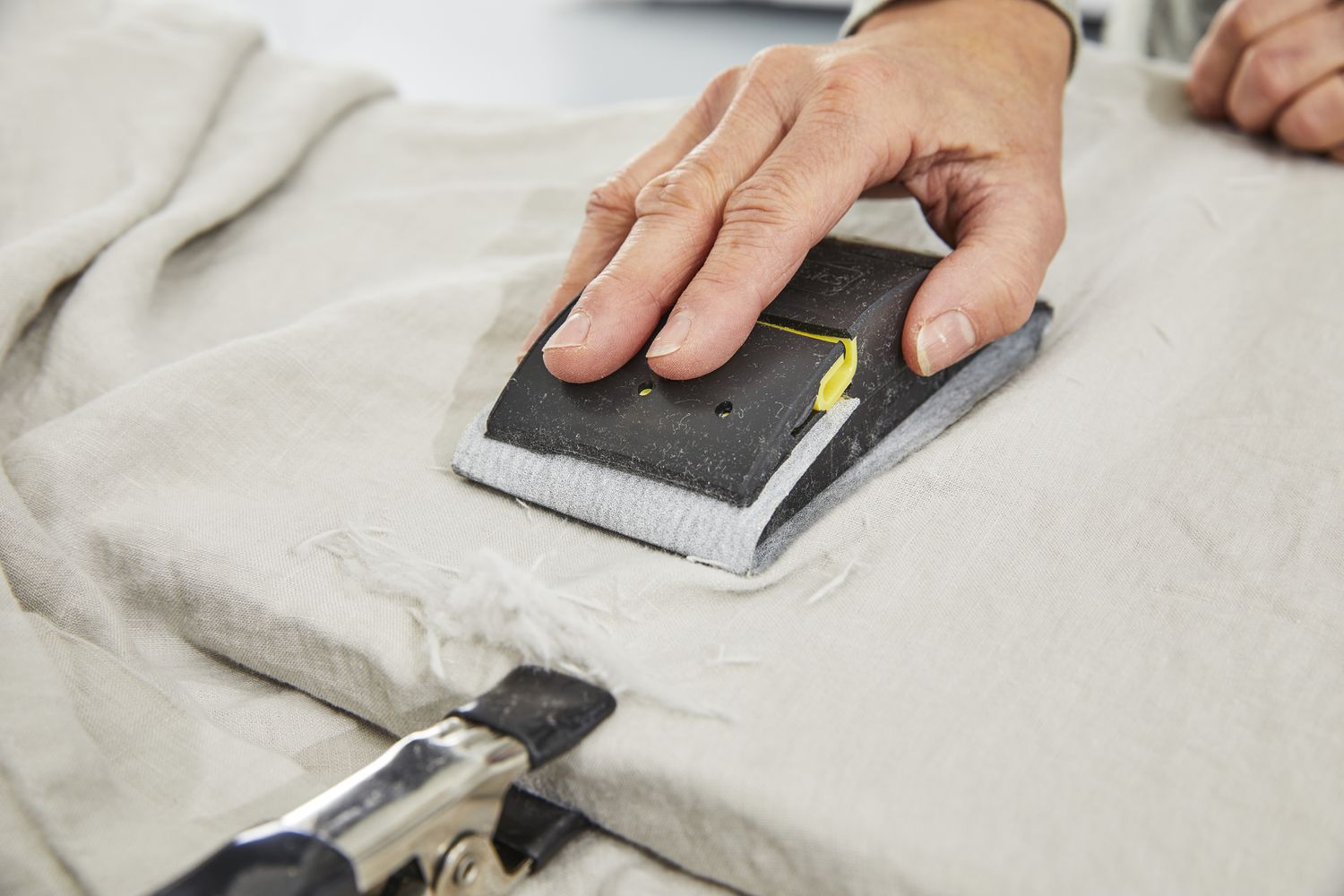 Hand uses a fabric tester against the Saatva Linen Sheet Set