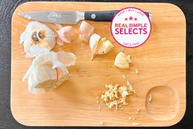 One of the Caraway Cutting Boards with chopped garlic and a utility knife on top