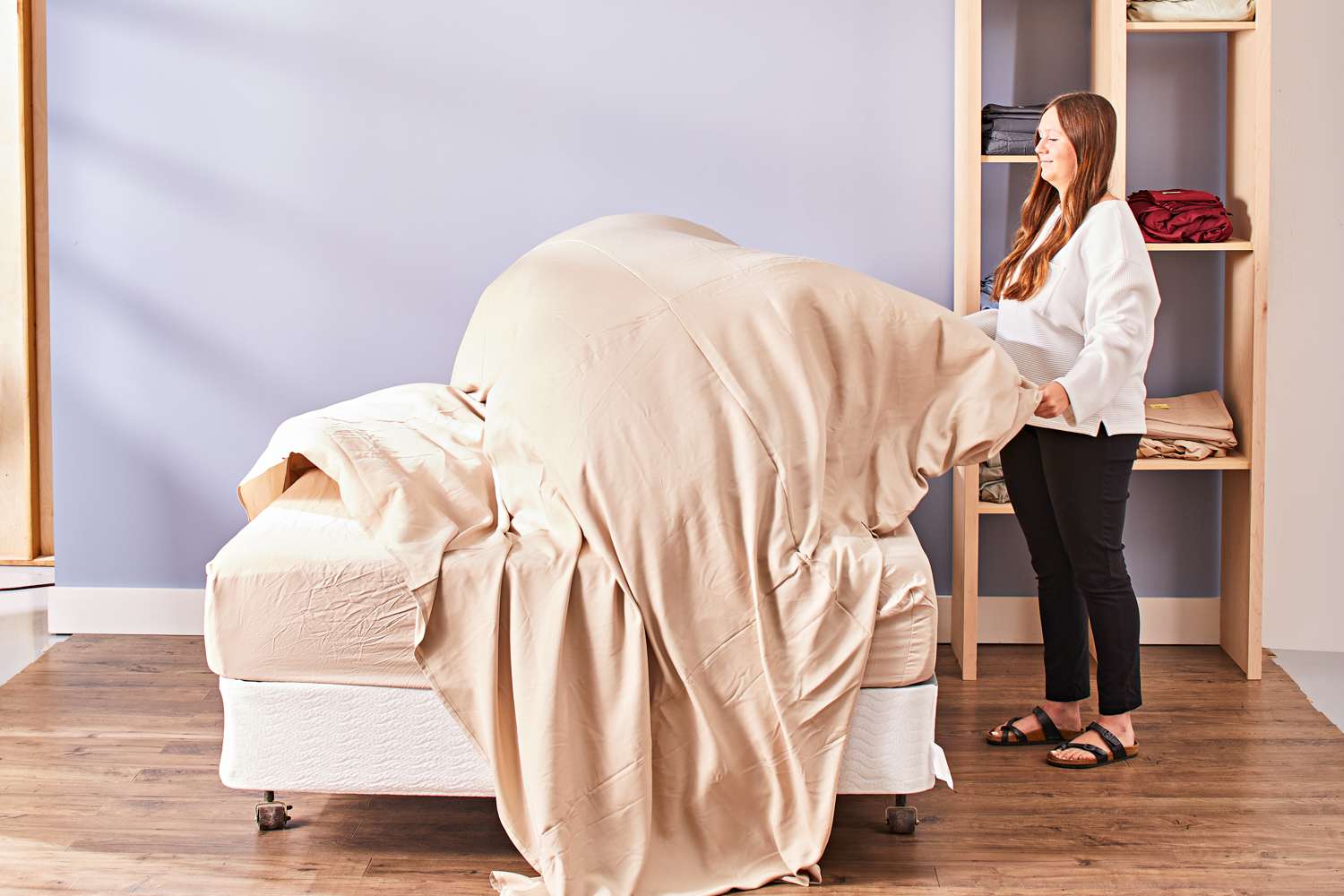 Person spreading a Cozy Earth Bamboo Sheet Set top sheet over a mattress