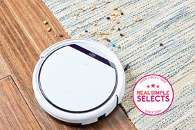 The ILIFEV3s Pro Robot Vacuum Cleaner cleaning up a mess from the wooden floor that has a patterned rug on it