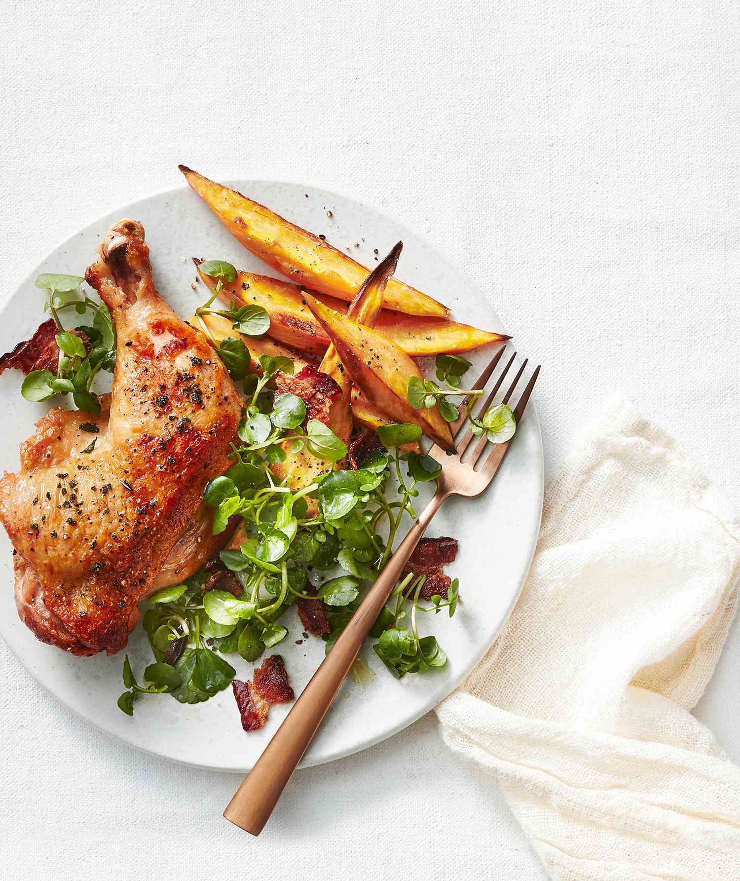 Sheet Pan Chicken and Sweet Potato Wedges Served on a White Plate With Metal Fork for Eating