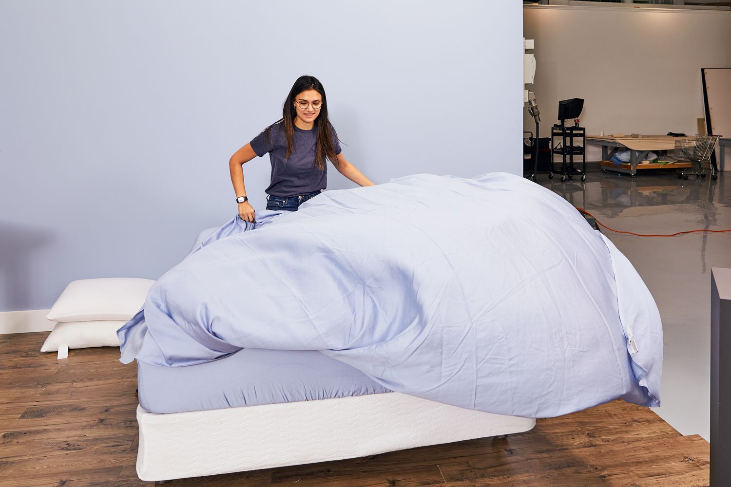 Person spreading the Sijo AiryWeight Eucalyptus Sheet Set on a bed 