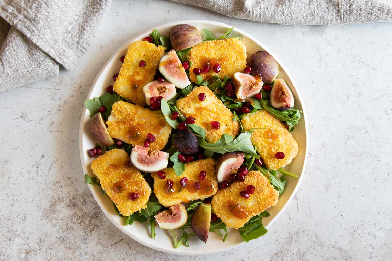 Overhead view of a bowl of Halloumi saganaki: pan-seared Greek cheese with pomegranates and figs.