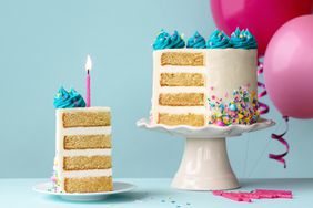 Birthday cake with layers and turquoise frosting, slice removed and one pink birthday candle